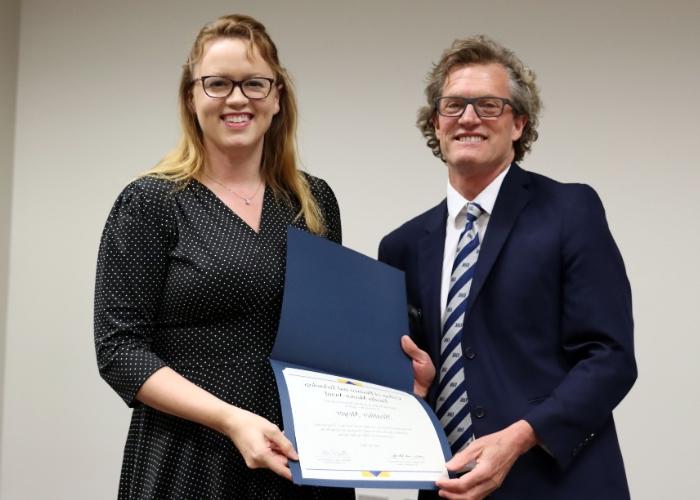 Man presenting an award to a woman.